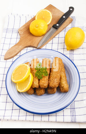 Poissons frits collés fabriqués à partir de poissons Lieu de l'Alaska dont la tranche de citron et le persil dans une assiette Banque D'Images