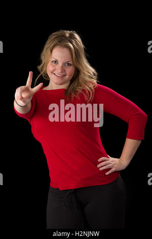 Jolie femme blonde, de sourire et de donner un signe de paix avec ses doigts Banque D'Images