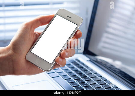 Smartphone avec écran blanc dans la main de business woman working in office with laptop Banque D'Images