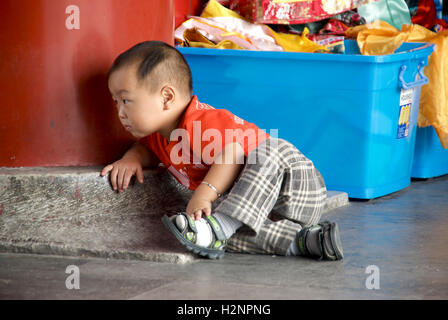 Un petit garçon chinois crawls et joue près de costumes à la Cité Interdite à Beijing, Chine. Banque D'Images
