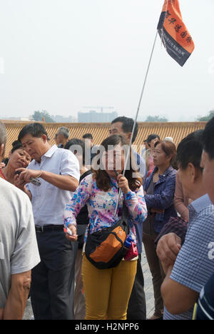 Un Chinois guide à la Cité Interdite de Pékin appelle les touristes chinois dans son groupe à l'attention. Banque D'Images