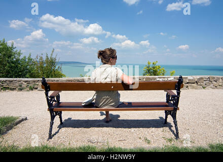 Jeune femme assise sur le banc avec vue du Lac Balaton à Tihany en Hongrie, Europe Banque D'Images