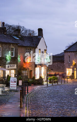 Lumières de Noël coloré égayer une sombre soirée d'hiver - Malham Village, Yorkshire Dales National Park, England. Banque D'Images