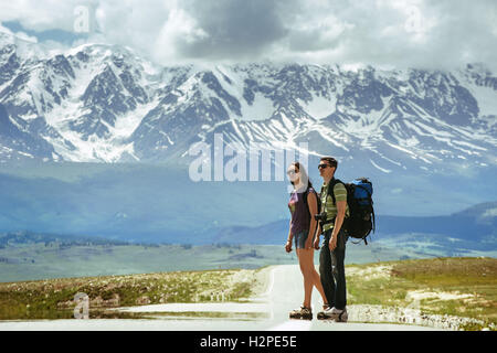 Couple de voyageurs reste sur la route dans les belles montagnes Banque D'Images