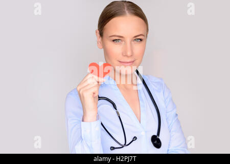 Portrait d'un beau médecin grave portant des uniformes médicaux et stéthoscope isolé sur fond gris Banque D'Images