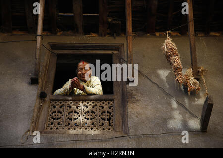 Kathmandu, Népal. 2e oct, 2016. Une Népalaise femme âgée donne à partir d'une fenêtre en bois ancien Village à Khokana, Lalitpur le dimanche 2 octobre 2016. © Skanda Gautam/ZUMA/Alamy Fil Live News Banque D'Images