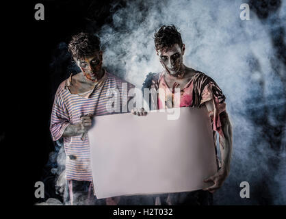 Deux hommes Zombies Holding Empty bannière blanche sur fond sombre et la fumée Banque D'Images