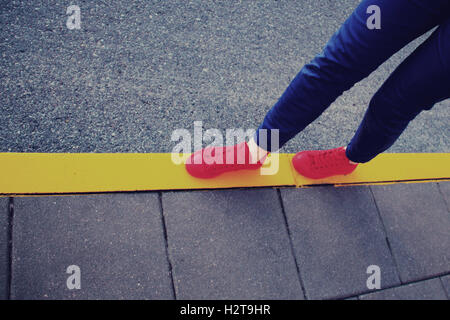 Red sneakers sur route jaune en ligne style vintage Banque D'Images