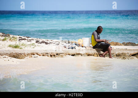 La Barbade Hastings Bay Fisherman jeune homme noir garçon sur la plage de pêche des autochtones pauvres mer ordures délabré délabrés privés pers Banque D'Images