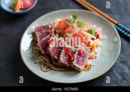 Thon poêlé en croûte de graines de sésame avec salade asiatique épicée et radis marinés Banque D'Images