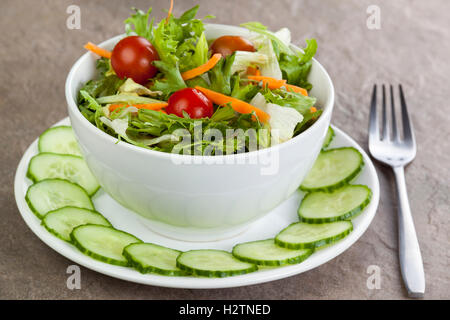 Bol de salade fraîche à la tomate et la carotte à l'intérieur un anneau de concombre plaqué sur une surface de travail en pierre naturelle Banque D'Images