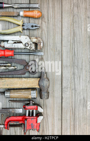 Vieux outils de travail et des instruments, dont un marteau, pinces, tournevis et autres sur fond gris en bois Banque D'Images