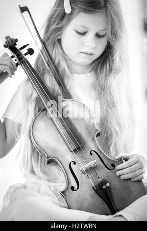 Image en noir et blanc d'une belle jeune fille aux cheveux longs jouant avec violon Banque D'Images