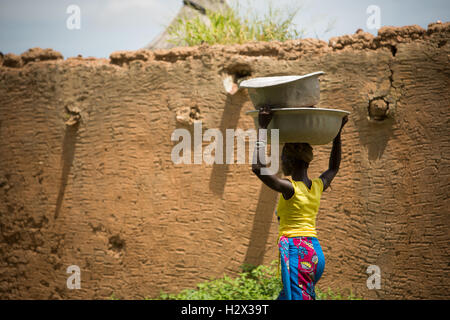 Une femme porte sur sa tête des bassins dans les régions rurales de Réo, Burkina Faso, du département Afrique de l'Ouest. Banque D'Images