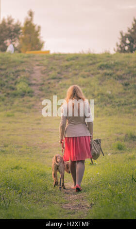 Vue arrière de l'embonpoint des jeunes adultes woman walking dog summer Banque D'Images