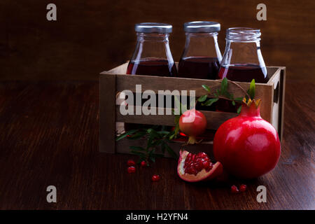 Jus de grenade et fruits sur fond de bois foncé, selective focus. Banque D'Images