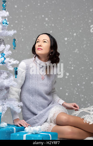 Belle fille japonaise avec des cadeaux dans l'arbre de Noël décoré, studio, prise de vue pour la couverture, l'arbre blanc Banque D'Images