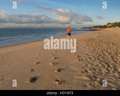 Man jogging sur la plage de Bournemouth tôt le matin, la lumière. Dorset, UK Banque D'Images