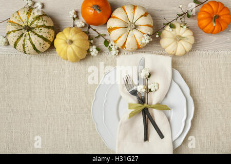 Fête de l'automne automne dîner de Thanksgiving table place setting with miniature citrouilles, assiette, couteau, fourchette et serviette sur fond de toile Banque D'Images