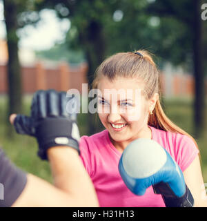 Jeune femme sportive de boxe d'entraînement avec un instructeur au parc. Entraînement à l'extérieur de remise en forme Banque D'Images