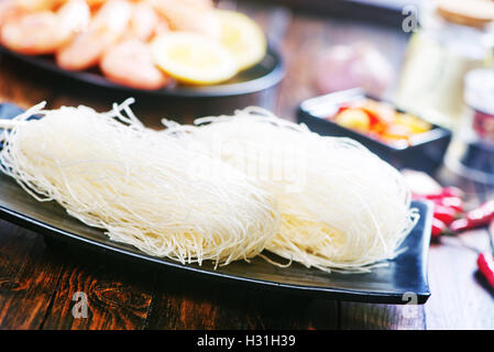 Les nouilles de riz dans une assiette et sur une table Banque D'Images