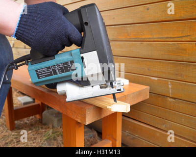 L'homme en bleu scies gants planche en bois Banque D'Images