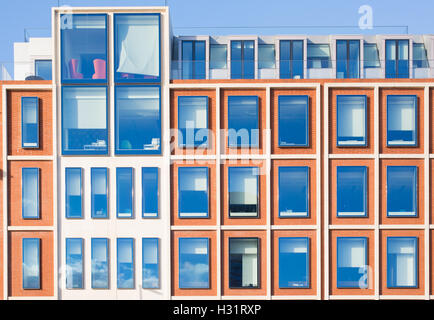 L'extérieur de l'immeuble moderne en briques rouges avec finition blanche. Ciel bleu reflété dans les fenêtres de verre Banque D'Images