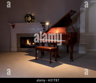 Le piano avec lampe de lecture avec cheminée rougeoyante et décorations de Noël en arrière-plan. Sélectionnez l'accent sur l'avant du piano. Banque D'Images