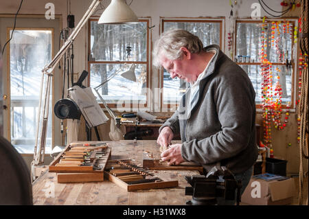 Un homme qui travaille dans son studio sur un oiseau en bois Sculpture sur bois. Banque D'Images