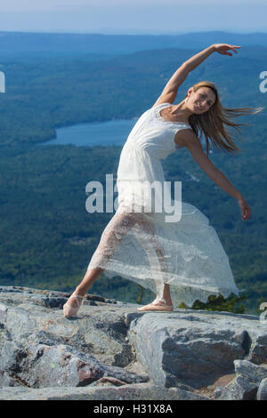 Danseuse en robe blanche dansant dans le vent au sommet de Mt. Kearsarge, New Hampshire. Banque D'Images