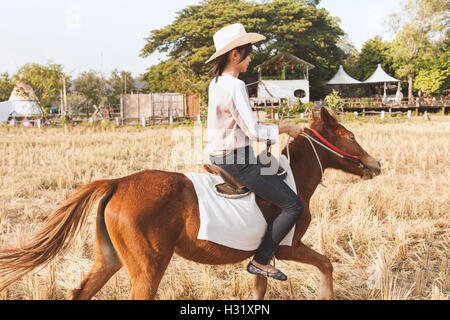 Belle jeune femme sourit à cheval sur le terrain avec des temps de détente . Sur le côté de la caméra. La liberté, la joie, le mouvement Banque D'Images