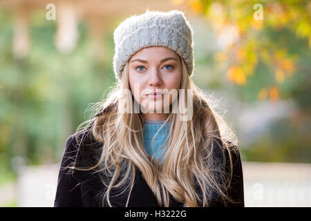 Portrait d'une jeune femme à l'extérieur. Elle porte un chapeau et est debout dans un parc. Banque D'Images