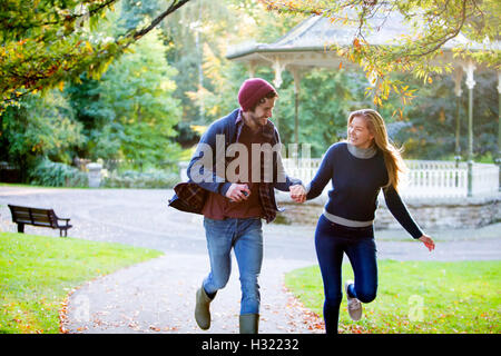 Jeune couple fonctionnant ensemble dans un parc en automne. Banque D'Images