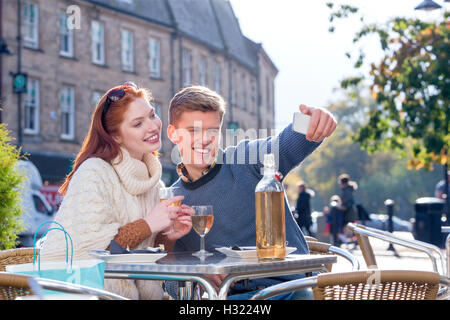 Un couple assis à l'extérieur en selfies un café. Banque D'Images