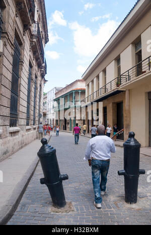 Un musicien cubain avec une guitare faite de bollards marche entre vieux canons dans la vieille Havane Banque D'Images