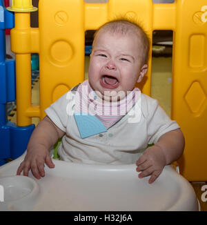 Baby sitting dans le bac avec siège bumbo, pleurer Banque D'Images