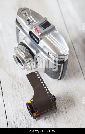 Une vieille caméra 35mm avec un rouleau de film assis près d'elle. Banque D'Images