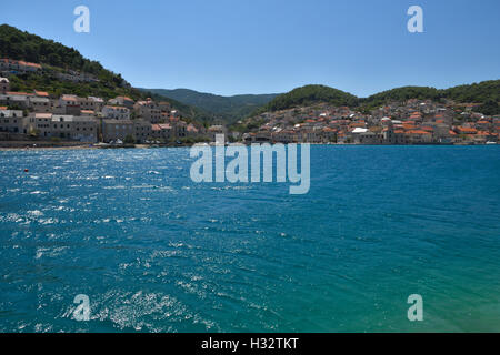 Petit village Pučišća avec eau bleu clair en premier plan, photo de l'île de Brac en Croatie. Banque D'Images