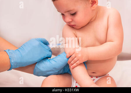 Close-up shot de pédiatre donnant une petite fille un an injection intramusculaire dans le bras Banque D'Images