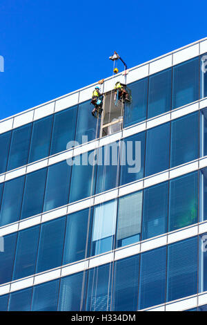 Deux ouvriers la réparation de fenêtre sur un grand bâtiment si suspendu par des cordes, Glasgow, Écosse, Royaume-Uni Banque D'Images