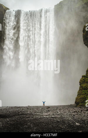 Personne avec les bras tendus devant, cascade Skógafoss, Région du Sud, Islande Banque D'Images