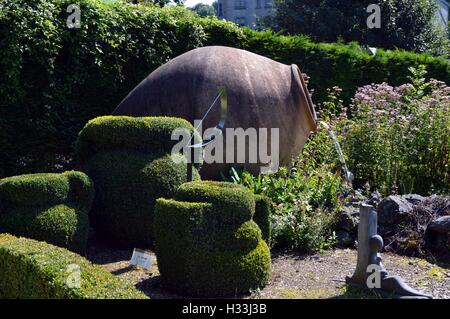 L'amphora énorme servant de fontaine au milieu de fort arbre et au milieu d'une pelouse. Banque D'Images