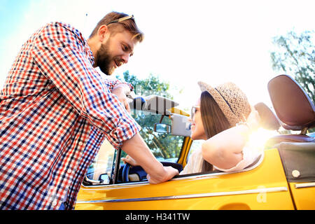 Couple. Belle jeune couple enjoying road trip in convertible et regarder avec le sourire Banque D'Images