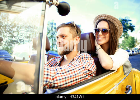 Couple. Belle jeune couple enjoying road trip in convertible et regarder avec le sourire Banque D'Images