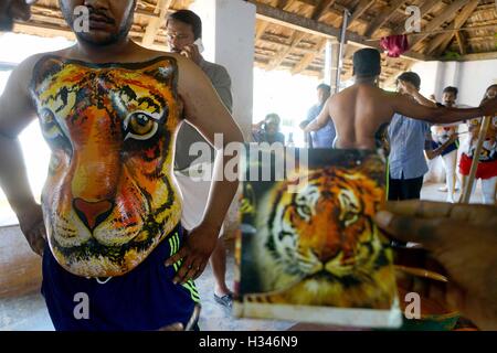 Danseurs formés obtenir leur corps peint aux couleurs tiger préparer participer à la célèbre Pulikali Kerala Thrissur Banque D'Images