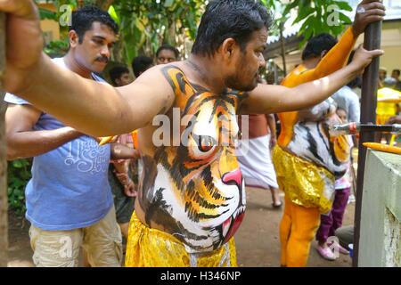 Danseurs formés obtenir leur corps peint aux couleurs d'un tigre se préparent à participer célèbre Pulikali Thrissur, Kerala Banque D'Images