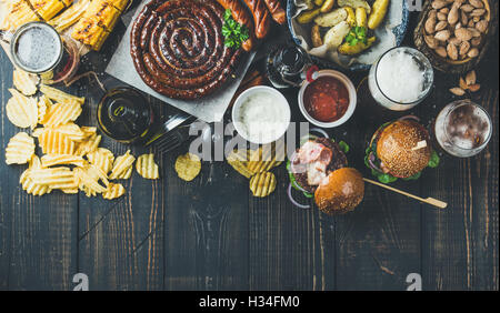 Variété de bières, saucisses, hamburgers, pommes de terre, maïs sur fond sombre Banque D'Images