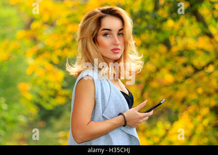 Belle fille avec des cheveux d'or d'un smartphone dans les mains Banque D'Images