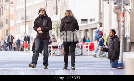 INNSBRUCK, Autriche - 1er novembre 2015 : la mendicité des réfugiés de l'aide dans les rues d'Innsbruck avec des gens qui marchent par. Banque D'Images