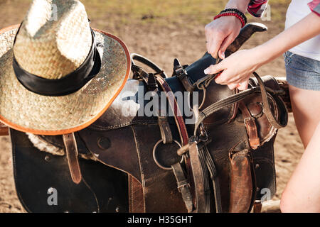 Selle de gros plan préparé pour l'équitation par jeune femme cowgirl Banque D'Images